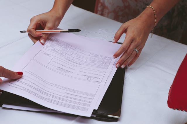 Person Holding a Pen and Documents