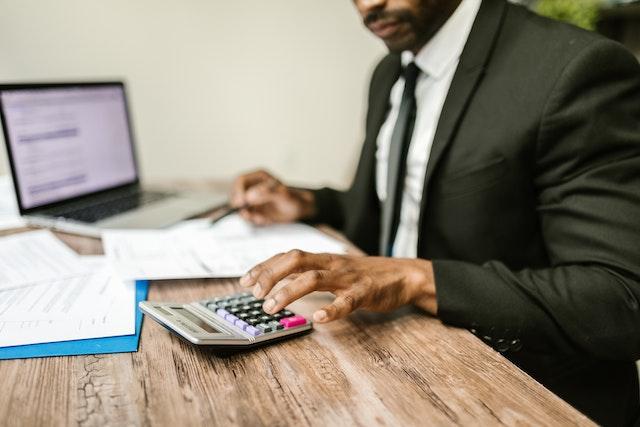 accountant using a calculator and noting things on his computer
