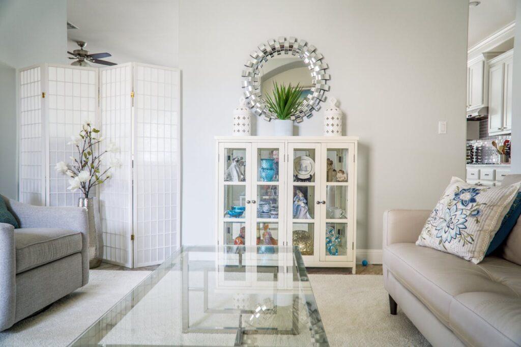 living room with white walls, white couches, and round mirror